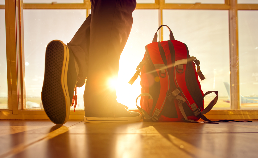 Traveler stands near the backpack at airport.
